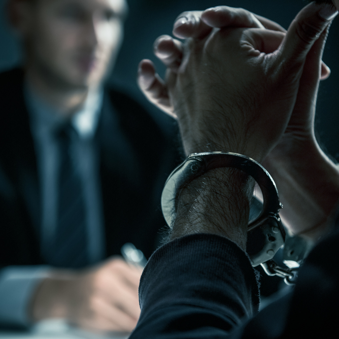 Handcuffed person seated across a desk